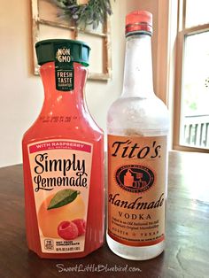 two bottles of liquid sitting on top of a wooden table