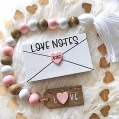 the love notes are laid out on top of a white furnishing with hearts and tassels