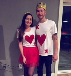 a man standing next to a woman in a red skirt and white t - shirt