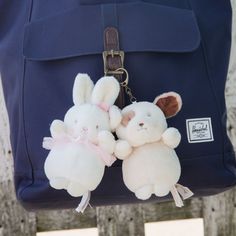 two stuffed animals are attached to a backpack