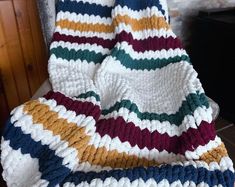 there is a crocheted blanket that has been folded up on a chair in front of a fireplace