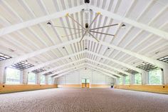 an empty horse barn with white walls and ceiling fan in the middle of the room