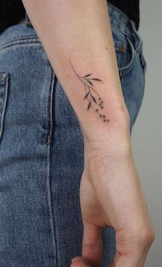 a woman's arm with a small flower tattoo on the left side of her wrist