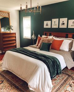 a bedroom with green walls, white bedding and rugs on the hardwood floor