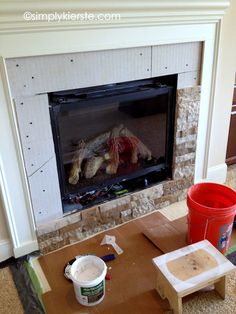 a fire place in the middle of a living room with construction materials on the floor