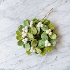 a green and white felt wreath on a marble surface