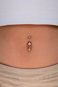 a woman's belly with a gold nose piercing on her right side, and a small diamond in the middle