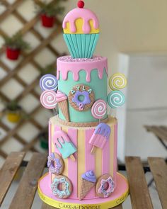 a three tiered cake is decorated with icing and candy items, including an ice cream cone