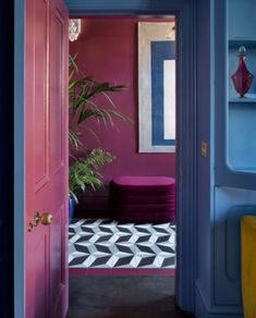 an open door leading to a living room with purple walls and black and white flooring