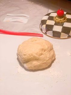 a ball of dough sitting on top of a counter next to a plate with a red handle