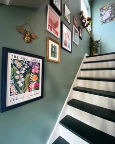 some pictures are hanging on the wall next to a stair case with black and white stairs