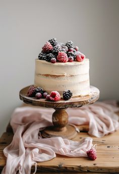 a cake with berries on top sitting on a wooden table