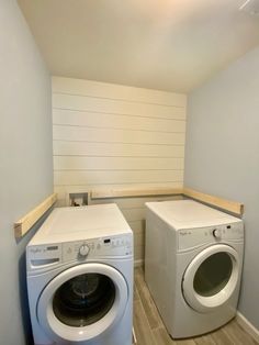 a washer and dryer in a small room with wood flooring on the walls