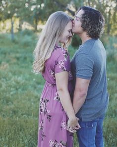 a man and woman are kissing in the grass