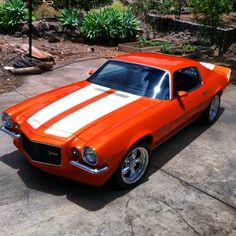 an orange and white muscle car parked in a driveway