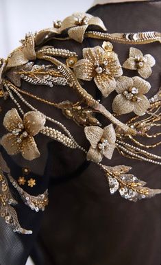 the back of a woman's dress with gold flowers and pearls on it,