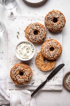 three bagels with sprinkles and cream cheese on a white tablecloth