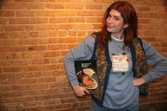 a woman standing in front of a brick wall