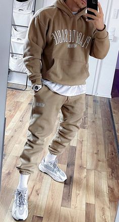 a man taking a selfie while wearing a brown hoodie and matching pants with white sneakers