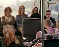 four women and two children are sitting on a bus with their backs to each other