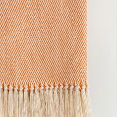 an orange and white blanket with fringes on it