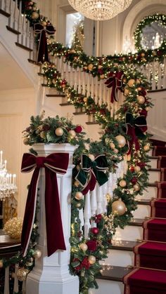 christmas decorations on the banisters and stairs are decorated with greenery, red ribbon, gold baubies and ornaments