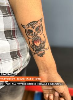 an owl tattoo on the arm and wrist is shown in black ink with red eyes