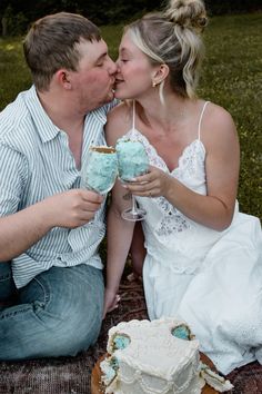 a man and woman kissing while sitting next to each other in front of a cake