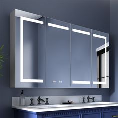 a bathroom vanity with two mirrors and lights on the wall above it, along with blue cabinets