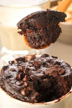 a close up of a spoonful of chocolate cake in a cup with cinnamon sticks