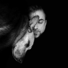 black and white photograph of a man sleeping with his head on the back of a dog