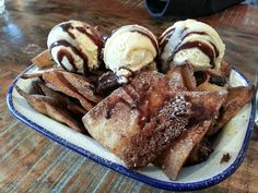 an ice cream sundae with chocolate sauce and waffles on a blue rimmed plate