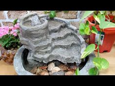 there is a rock fountain in the middle of some plants