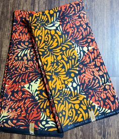 two orange and black patterned napkins sitting on top of a wooden floor next to each other