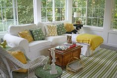 a living room filled with white furniture and lots of yellow pillows on top of them