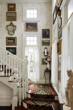 a white staircase with pictures on the wall above it and a rug in front of them