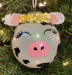 a christmas ornament with a pig face and flowers on it's head