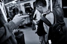 two people standing on a subway looking at their cell phones