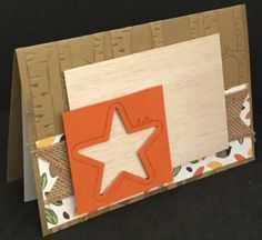 an orange and white card with a star cut out of it's side on a black surface