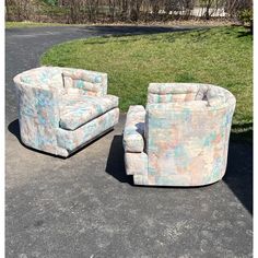 two chairs sitting next to each other on top of a parking lot with grass in the background