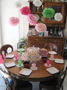 a dining room table with paper flowers and plates on it's centerpieces