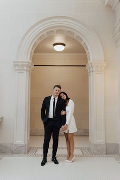 a man and woman posing for a photo in front of an arched doorway at the entrance to a building