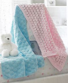 a white teddy bear sitting on top of a bed next to a crocheted blanket