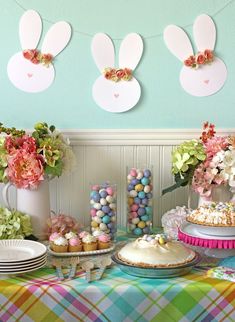 a table topped with cakes and cupcakes next to bunting banners on the wall