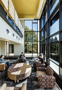 two people sitting on couches in a large room with lots of windows and floor to ceiling windows