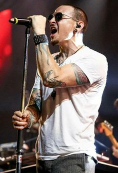 a man with tattoos on his arm singing into a microphone