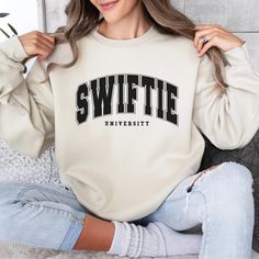 a woman sitting on the floor wearing a sweater with swiffe university written on it