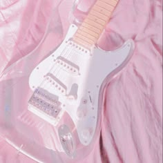 an electric guitar in a clear plastic case on a pink sheeted surface with the top section missing