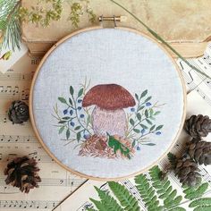 a mushroom with leaves and pine cones on top of sheet music next to evergreen needles