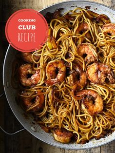 a skillet filled with shrimp and noodles on top of a wooden table next to a red sign that says cooking club recipe